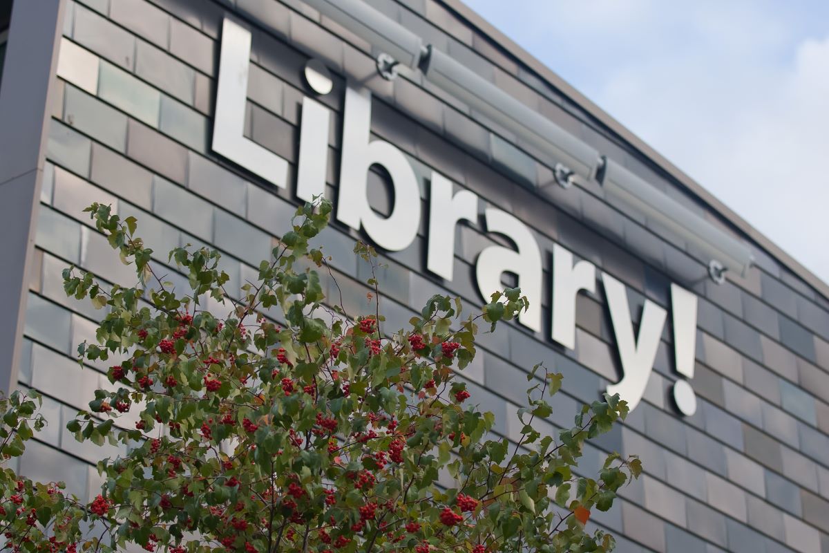 Library logo sign on building outside during the day.